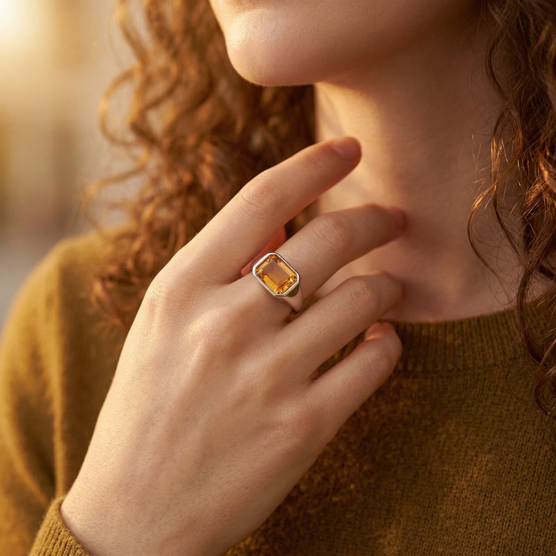 Woman wearing the silver emerald-cut citrine ring on her finger, paired with a mustard yellow sweater.