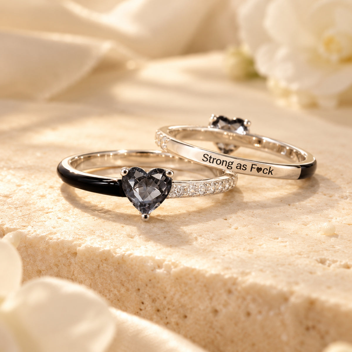 Front and back of the same silver black-heart enamel ring; rear-band engraving reads Strong as F♥ck.