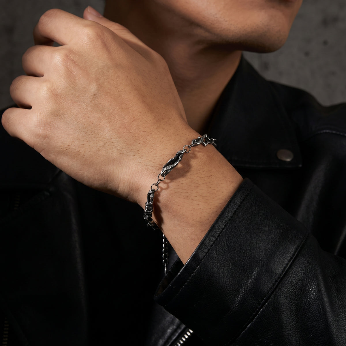 Oxidized silver chain bracelet worn on a man's wrist with a black leather jacket.