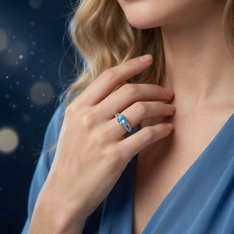 Azurella round natural topaz ring in sterling silver worn on a woman's hand with a soft bokeh background.