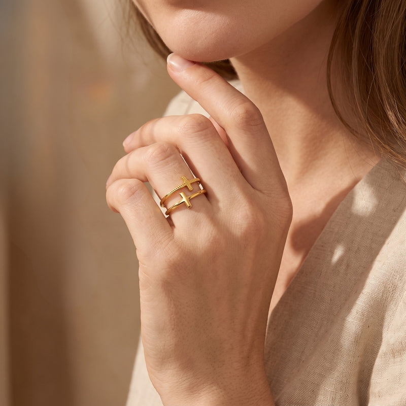 Model wearing the gold-tone double cross ring while touching her chin.