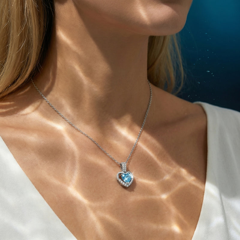 Heart-cut aquamarine platinum necklace worn by a model with shimmering water-like light patterns on her skin.