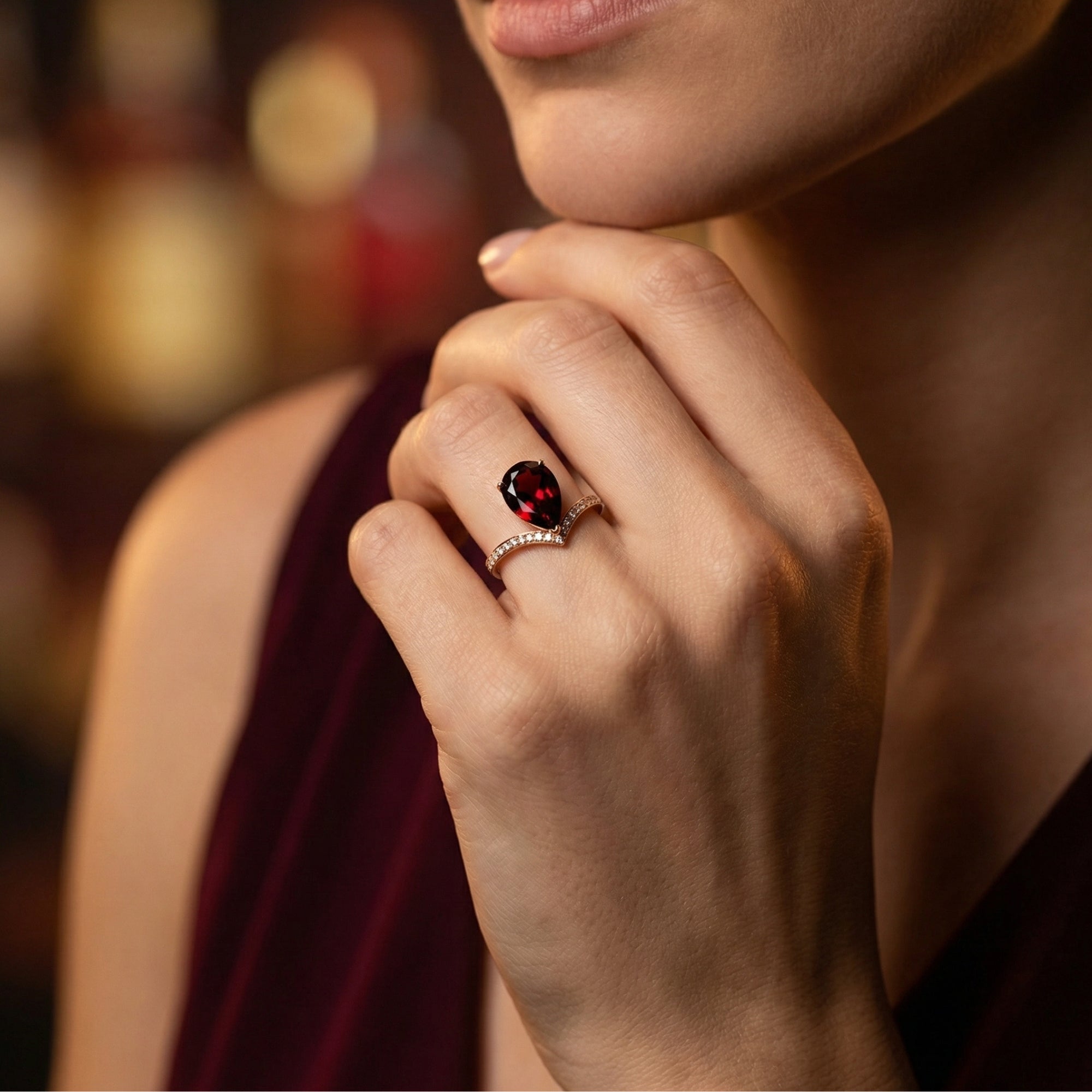Model wearing the Crimson Apex pear cut garnet ring in 18K rose gold on her finger, showing scale and hand placement.