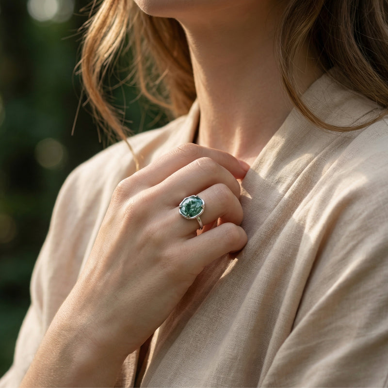 Woman wearing the organic flow moss agate ring in sterling silver on her finger, paired with a linen shirt.