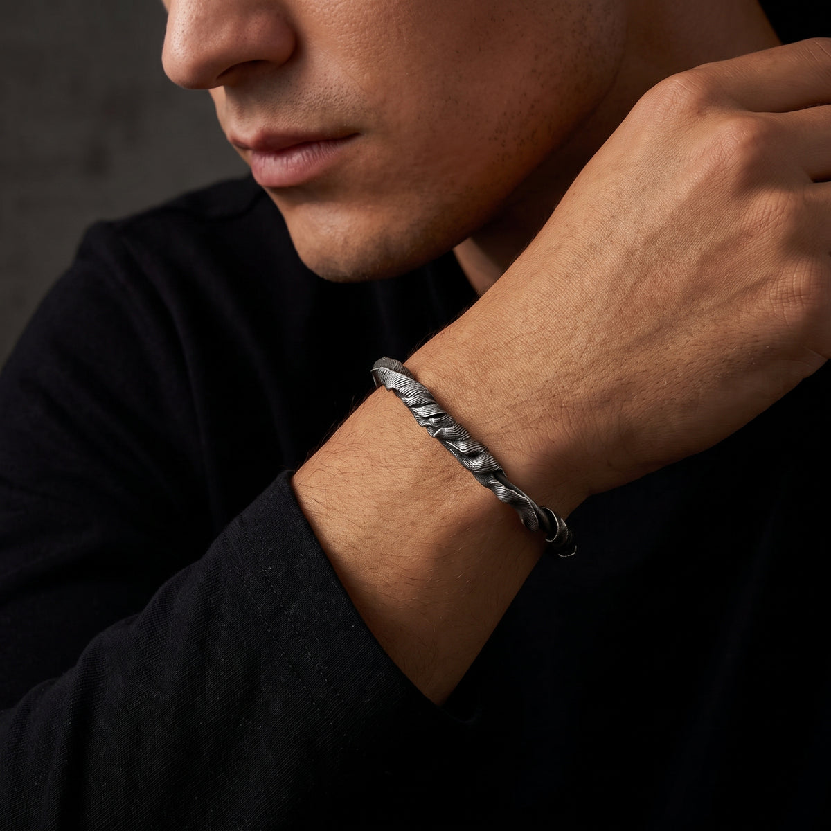 Close-up view of a man wearing the silver feathered twist cuff bracelet on his wrist.