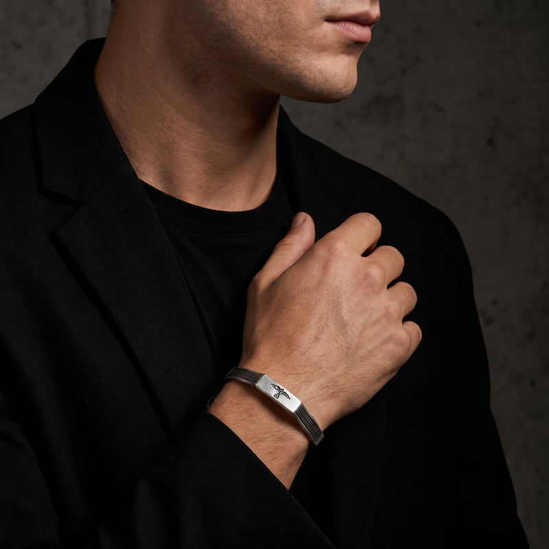 Silver grooved raven cuff bracelet worn on a man's wrist with a black suit jacket and tee.