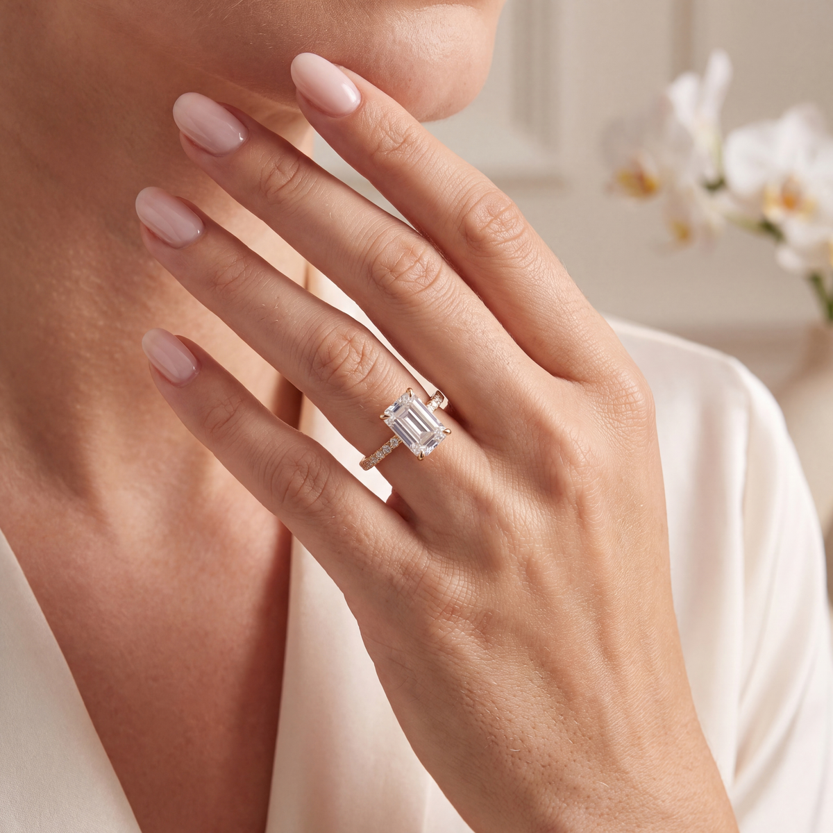 Yellow gold emerald cut moissanite engagement ring worn on a model's hand.