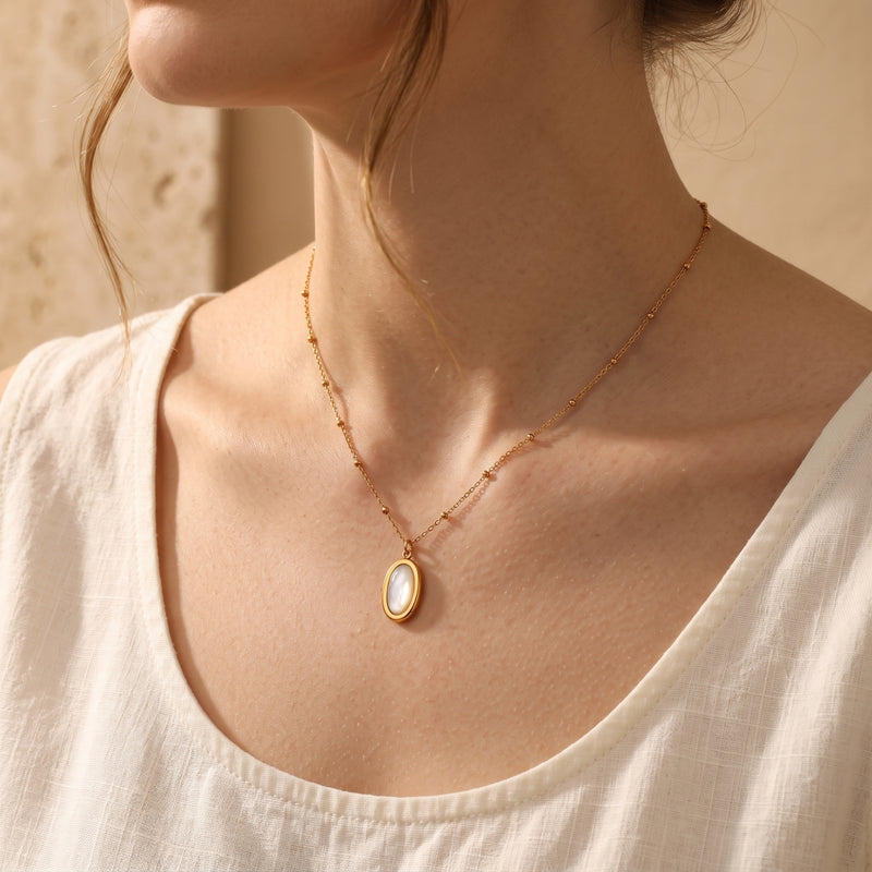 Gold mother of pearl pendant necklace worn on a beaded chain.