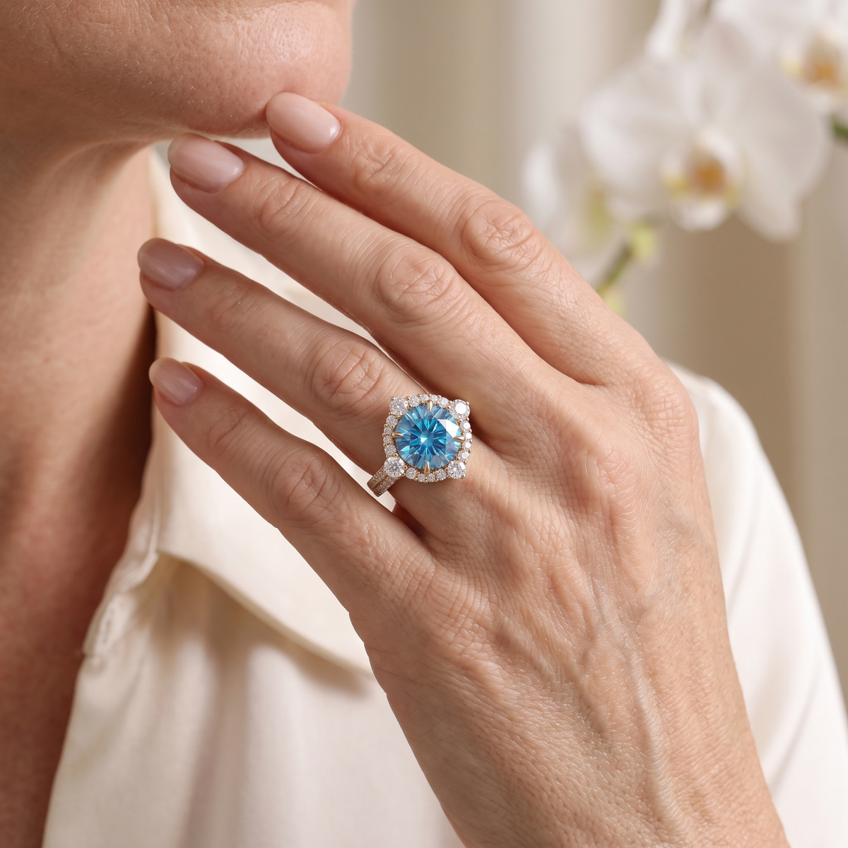 Close-up lifestyle view of round blue moissanite halo engagement ring in rose gold worn on hand