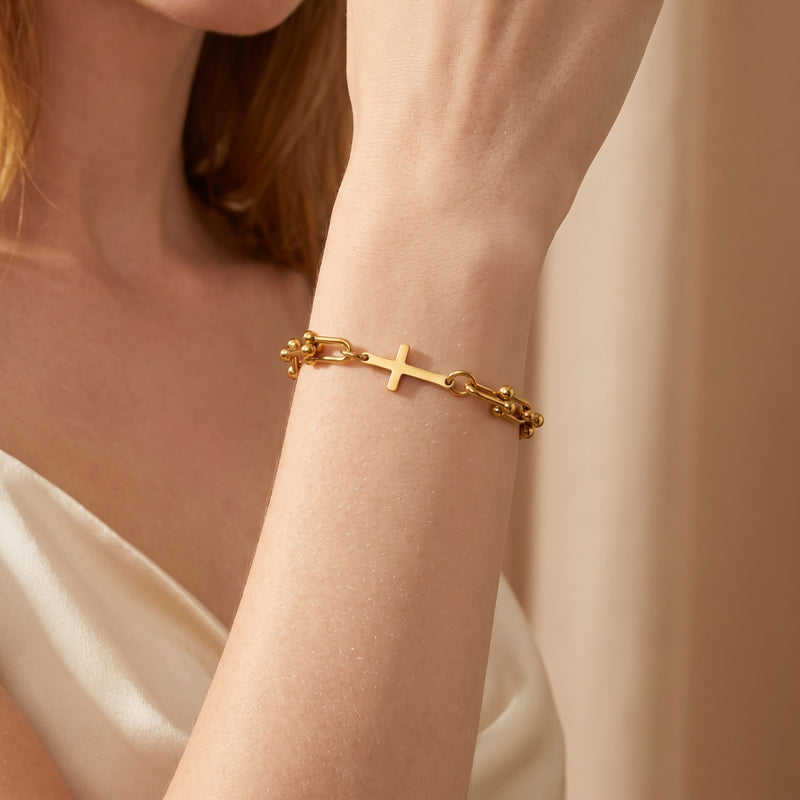 Close-up of a woman wearing the gold-tone horizontal cross U-link bracelet on her wrist.