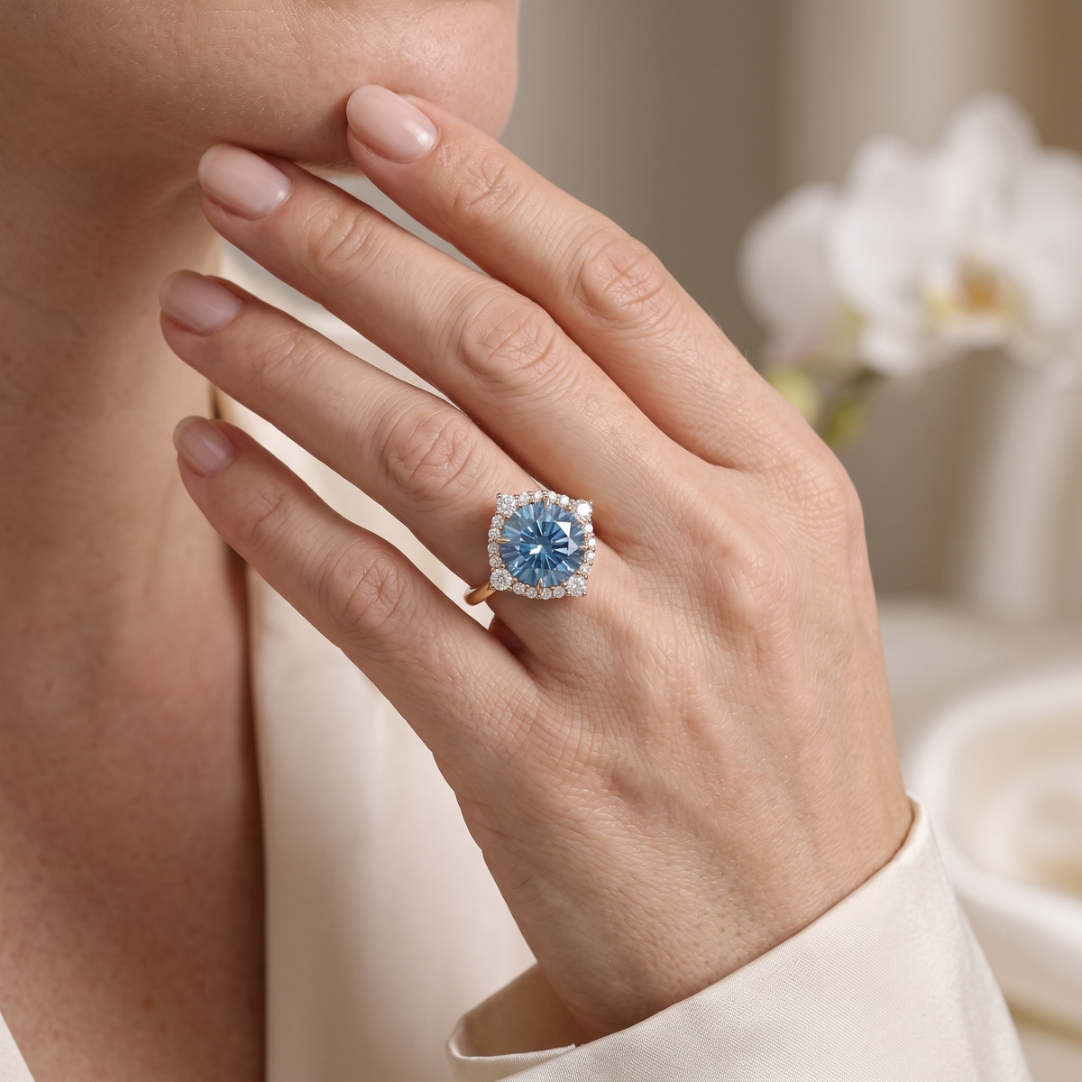 A rose gold blue moissanite halo ring worn on a woman's hand near her chin.