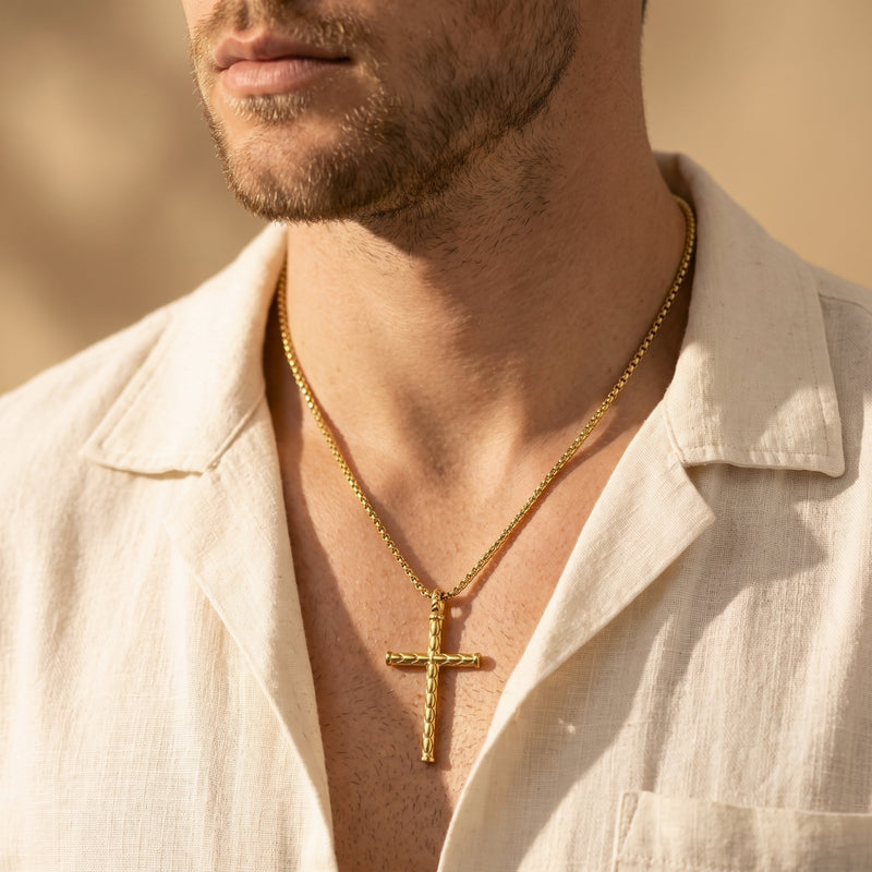 Close-up of a man wearing a gold-tone segmented cross necklace with an open white shirt.