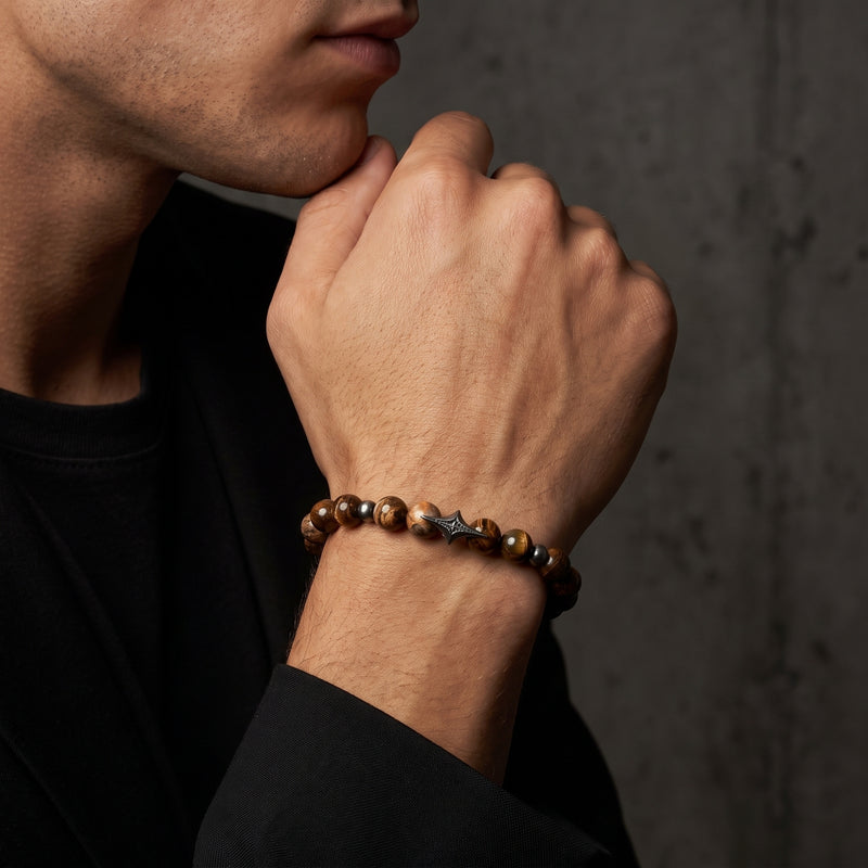 North Star beaded bracelet worn on a man's wrist as he rests his chin on his hand