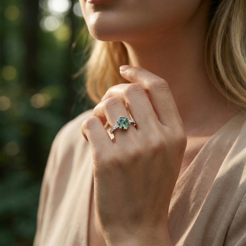 Model wearing a hexagonal moss agate sterling silver ring on her finger in a natural outdoor setting.