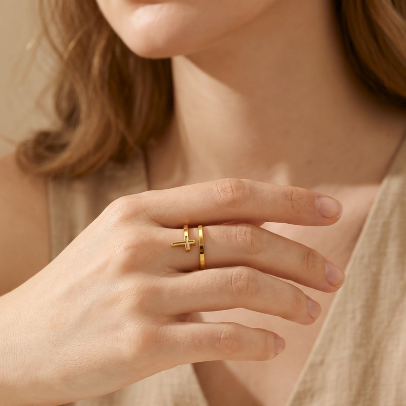 Close-up of a person wearing the gold-finish open-wrap cross ring on a middle finger.