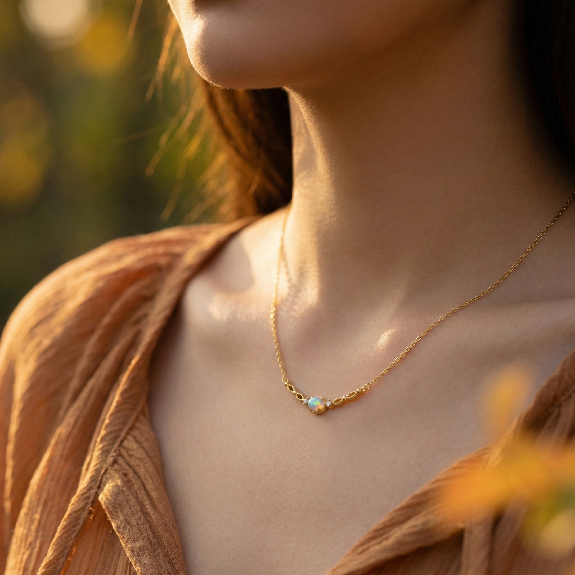 Model wearing the gold-tone Lumisara pendant necklace with an oval white opal October birthstone.
