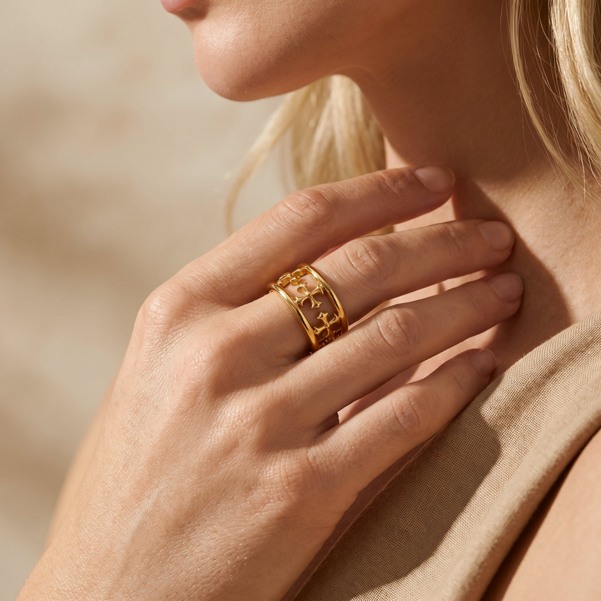 Close-up of a model wearing the gold-tone open cross cuff ring, hand resting near her neck.