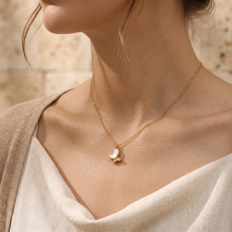 Gold mother of pearl butterfly necklace worn by a model against a neutral background.