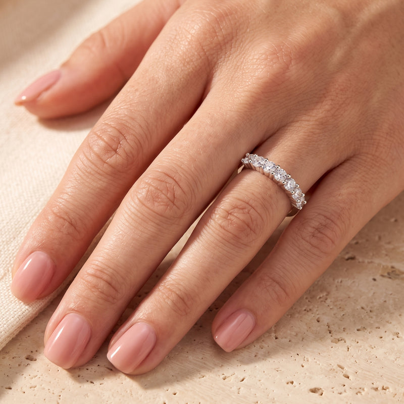 Seven-stone S925 sterling silver promise ring with round-cut stones worn on a woman's hand.