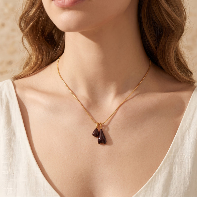 Marais gold pendant necklace with burgundy double drops worn by a model to show the necklace length.