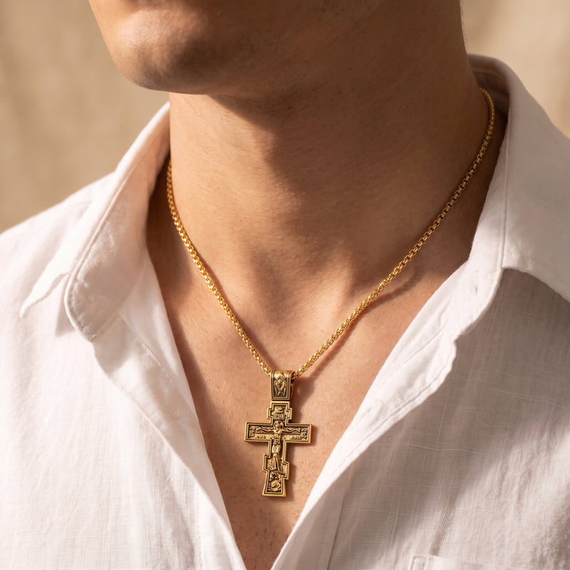 Close view of a man wearing a gold-tone Eastern cross pendant over an open-collar white shirt.