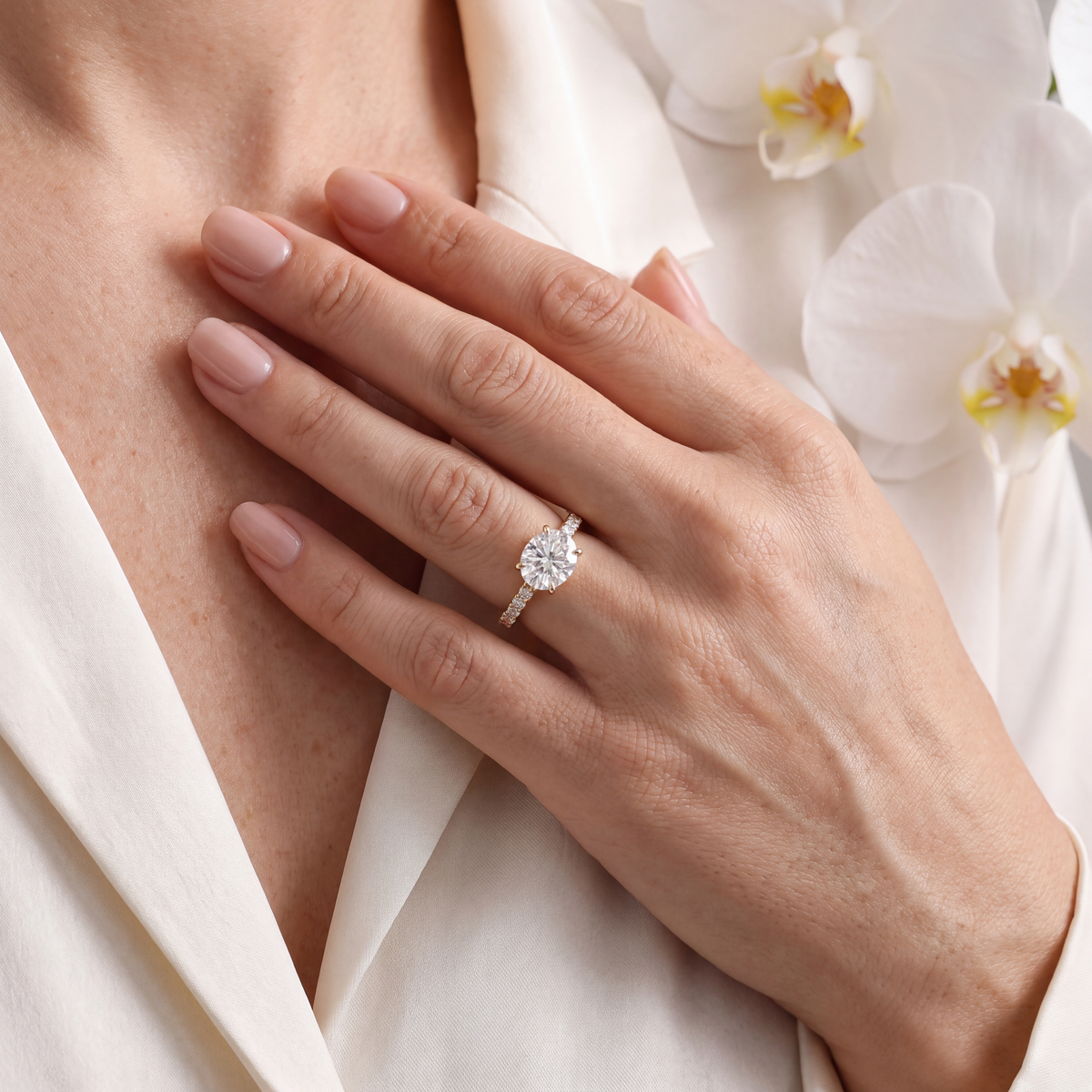 Gold moissanite engagement ring with a round center stone worn on a hand.