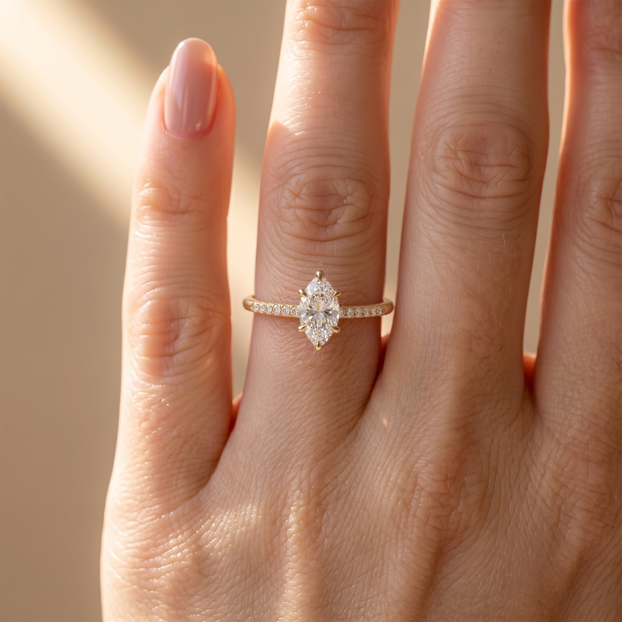A close-up view of a yellow gold marquise-cut moissanite engagement ring on a hand.
