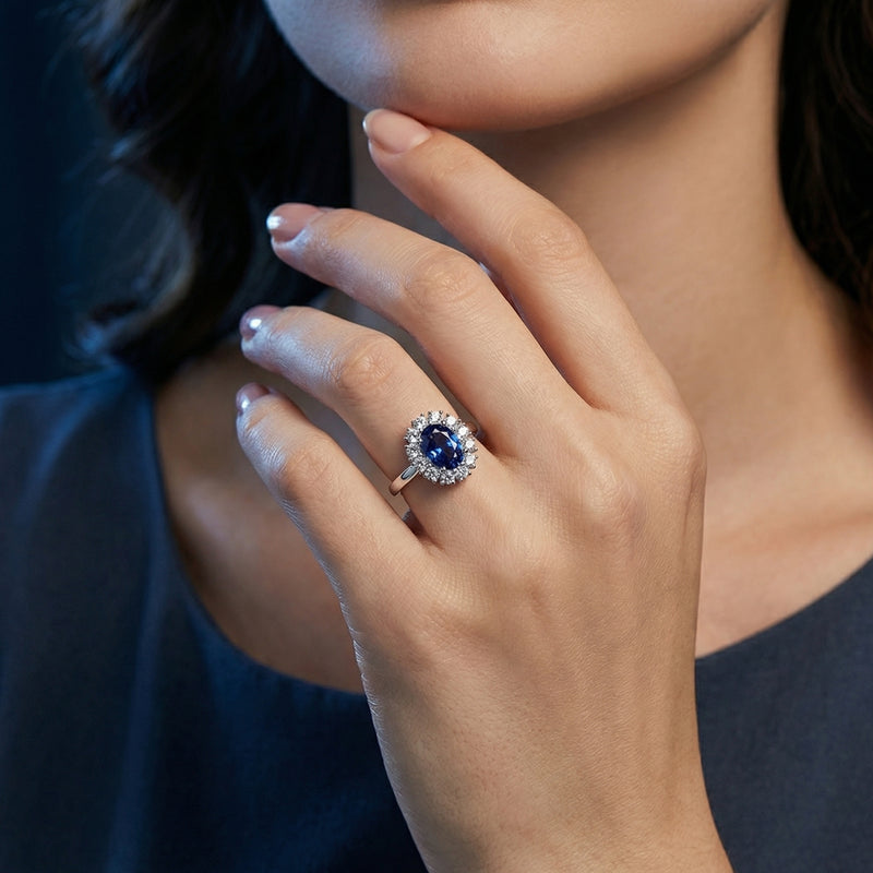 The Sylviana oval tanzanite halo ring in sterling silver worn on a model's ring finger.