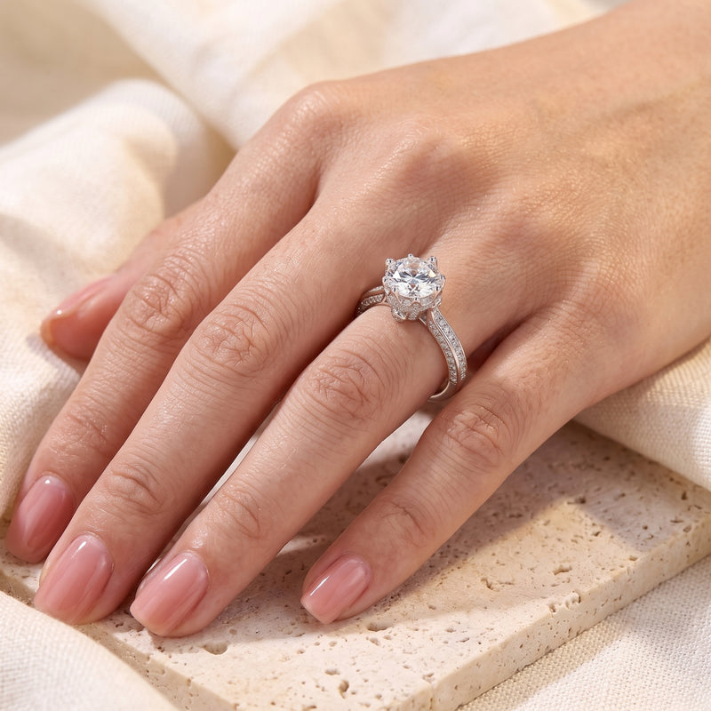 Round brilliant cut sterling silver crown promise ring shown on a woman's hand.