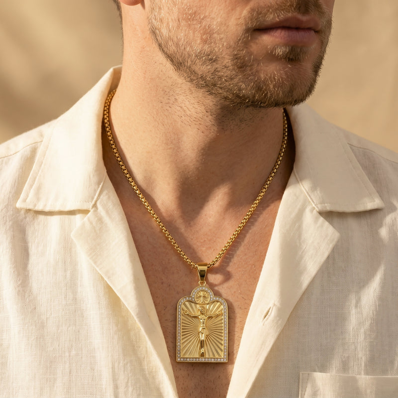Gold-tone arched crucifix necklace worn by a man in an open cream shirt.