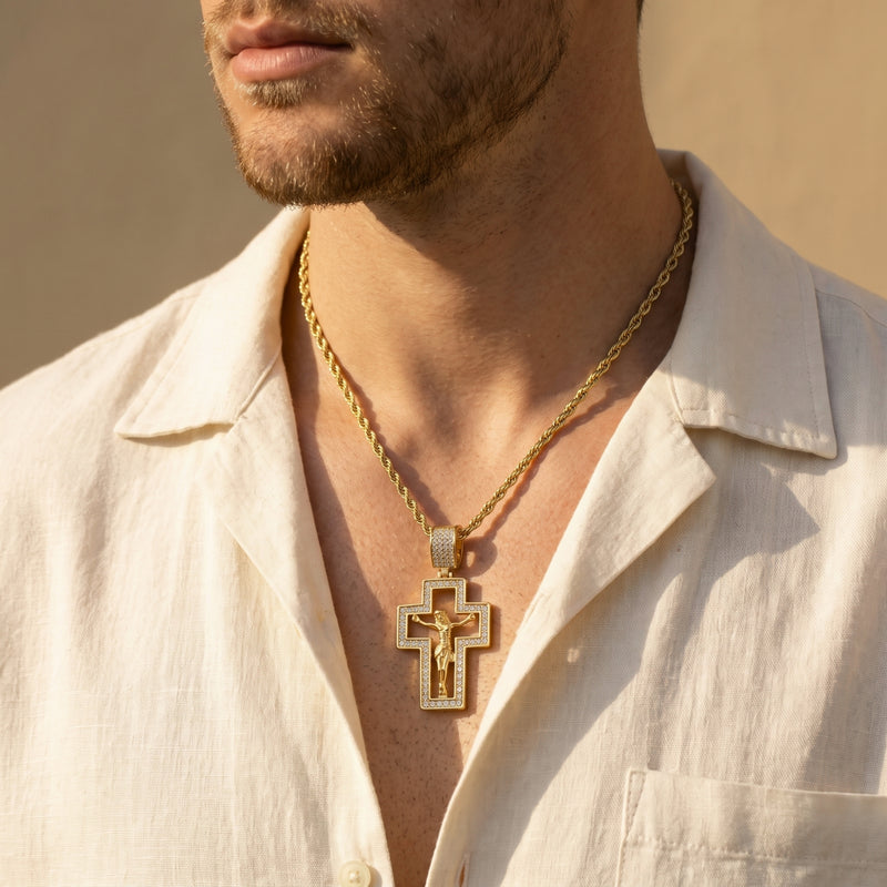 Man wearing a gold-tone cutout crucifix necklace over an open cream collared shirt.