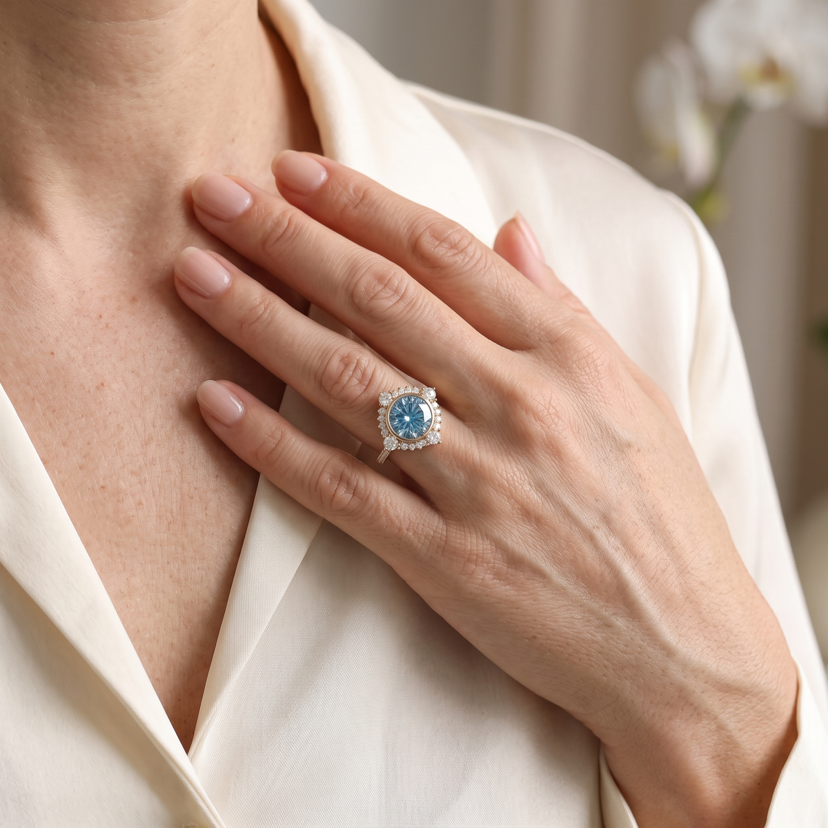 A model wearing a yellow gold halo ring with a brilliant blue moissanite center stone.