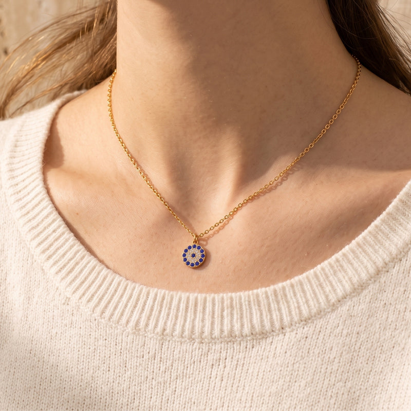 18K gold PVD Stellis pendant necklace with blue and white pave stones worn on a woman's neck.