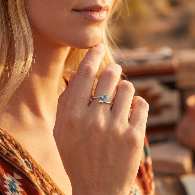 Woman wearing the silver Cibola turquoise bypass ring on her finger in a warm, outdoor setting.