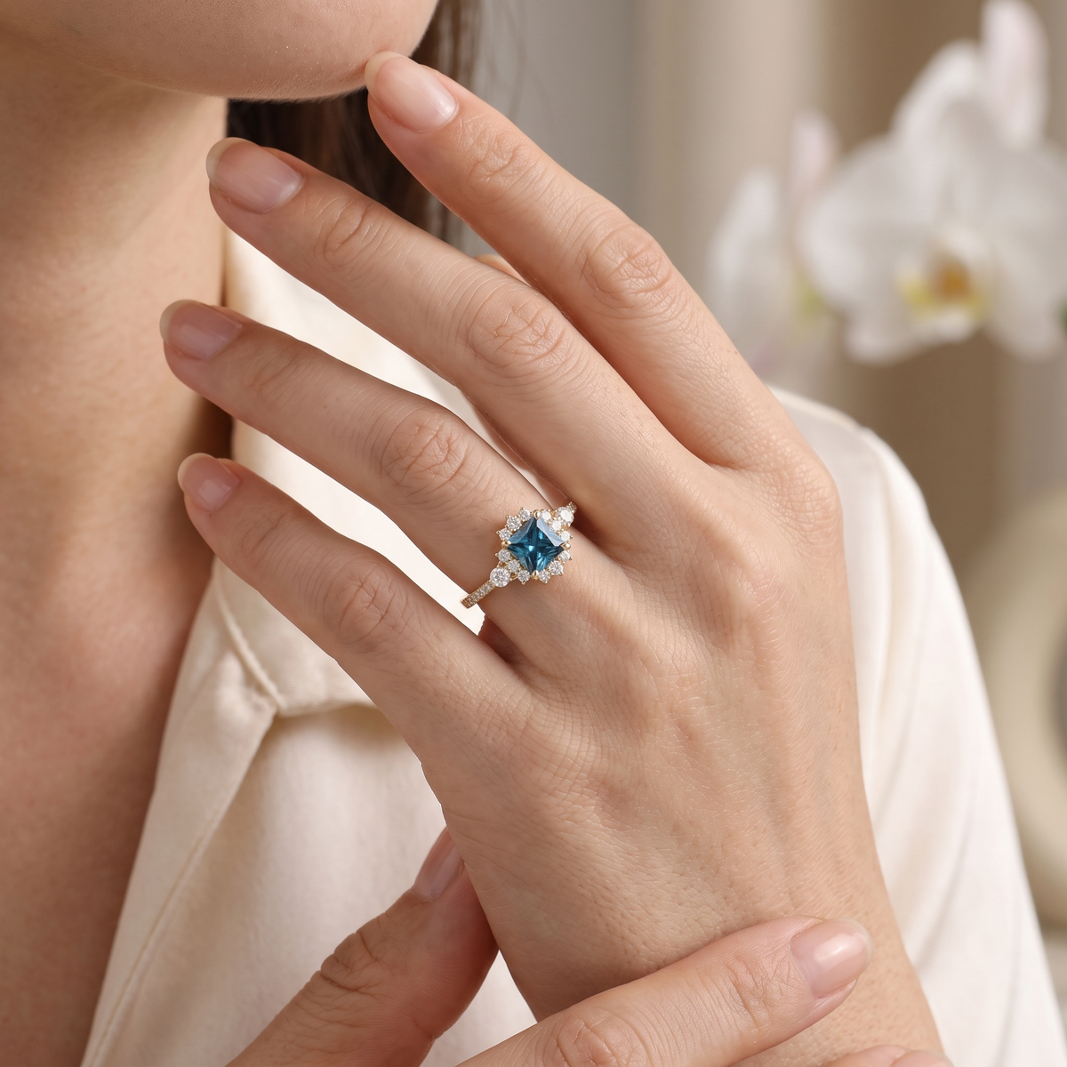 Woman wearing a rose gold princess cut teal blue moissanite halo ring on her ring finger.