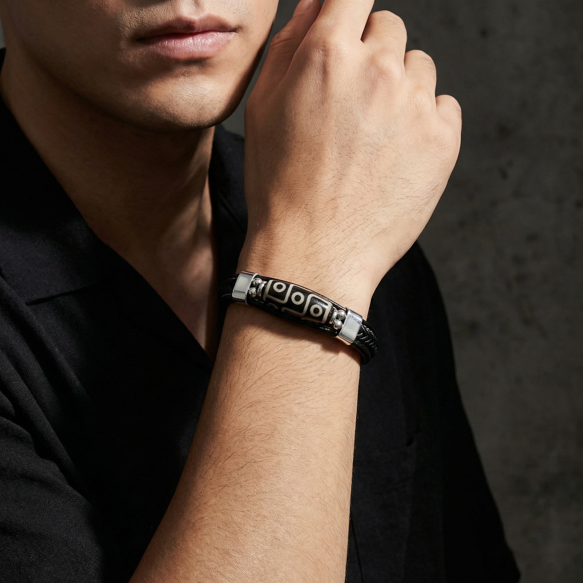 The Echelon men's black leather bracelet with silver stainless steel centerpiece worn on a model's wrist.