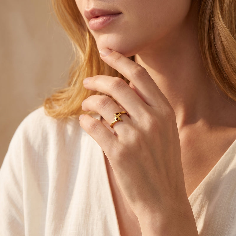 A woman wears the gold-tone openwork cross ring while touching her chin.