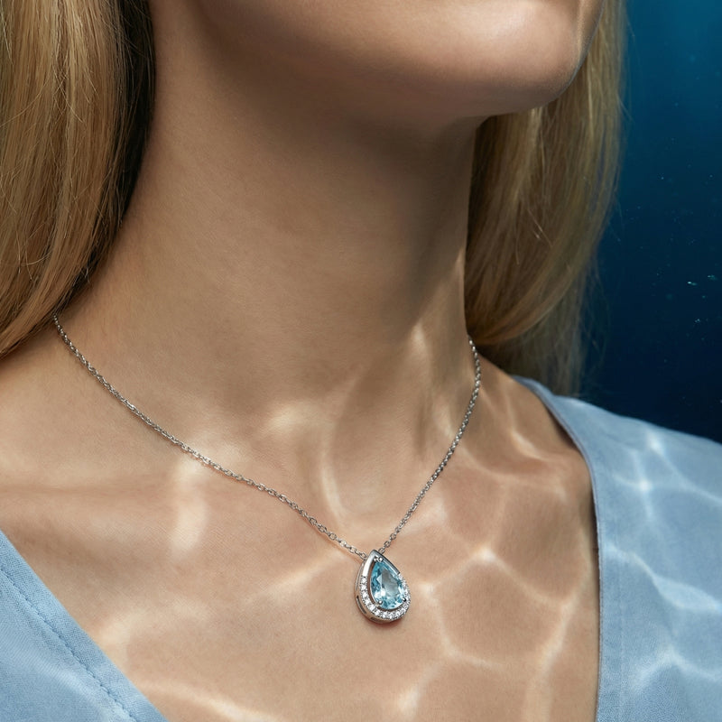 Lorelia pear cut aquamarine necklace in 18K white gold worn by a model with shimmering water light reflections.