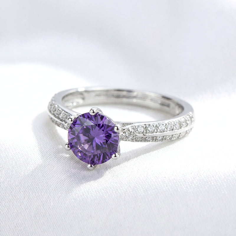 Macro view of a round-cut purple simulated amethyst in a sterling silver milgrain split-shank setting.