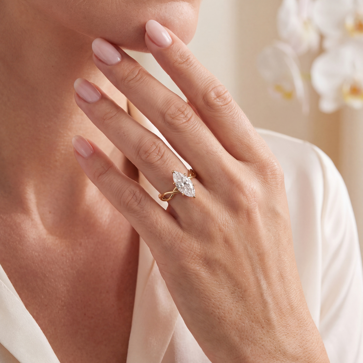 Gold marquise moissanite engagement ring worn on a model's hand.