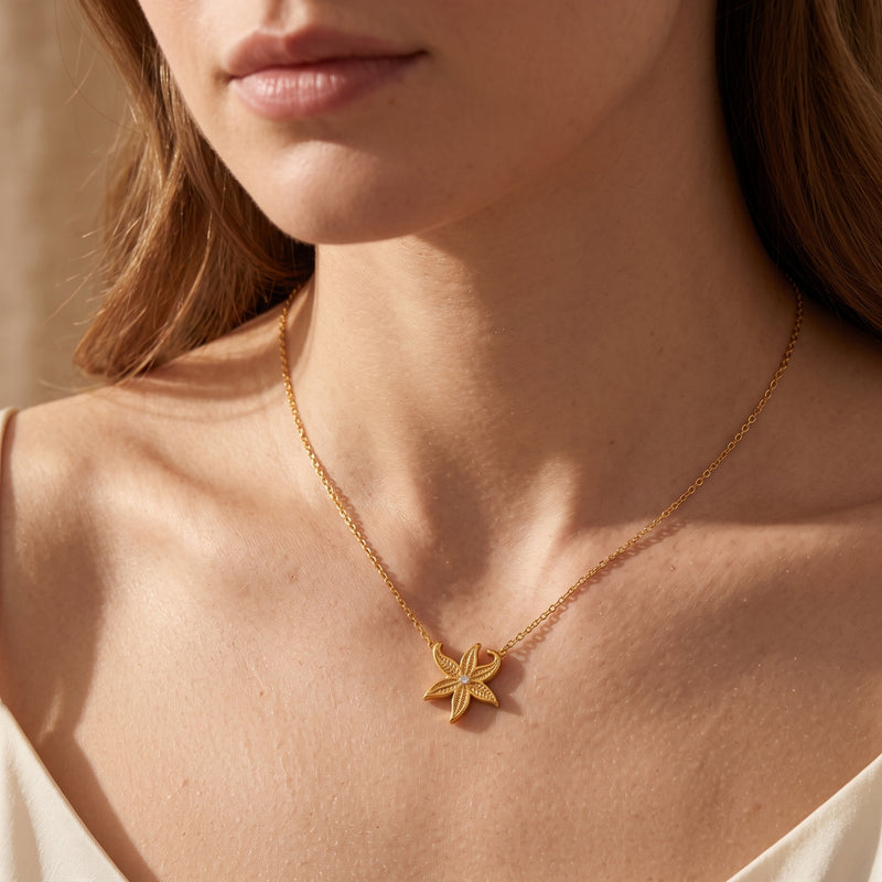 Gold starfish necklace worn on a woman's neck, showcasing the 18K gold PVD finish and adjustable chain.