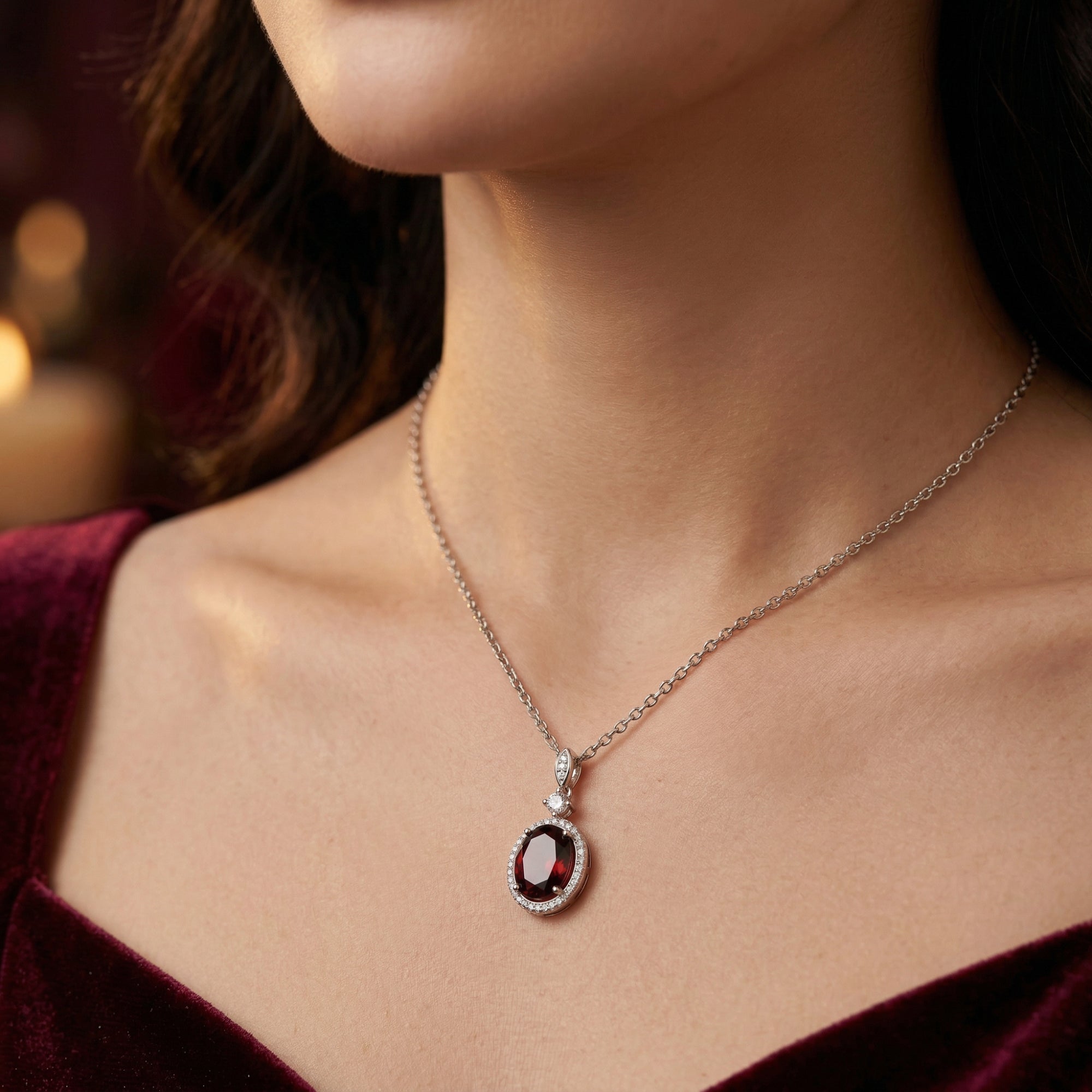 Model wearing the Kaelia oval garnet necklace in sterling silver against a dark red velvet dress.