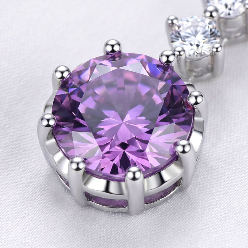 Macro view of a round purple simulated amethyst in a multi-prong sterling silver setting.