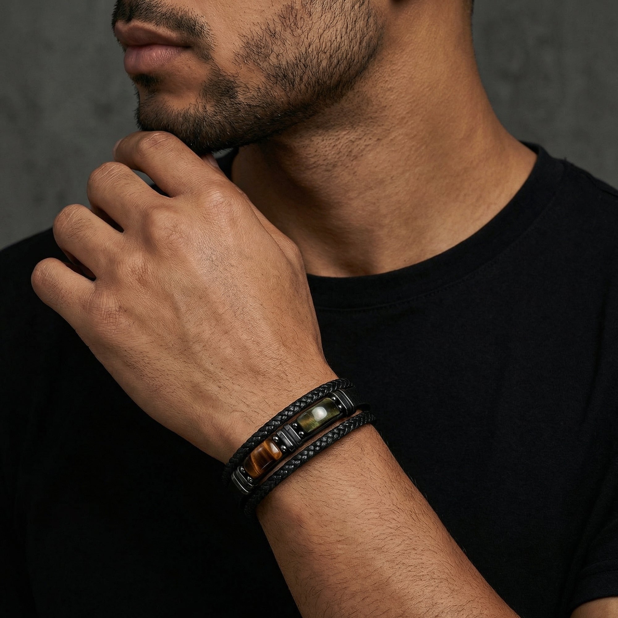 Men's black braided leather bracelet with tiger's eye cabochon stones and 316L black stainless steel worn on a wrist.
