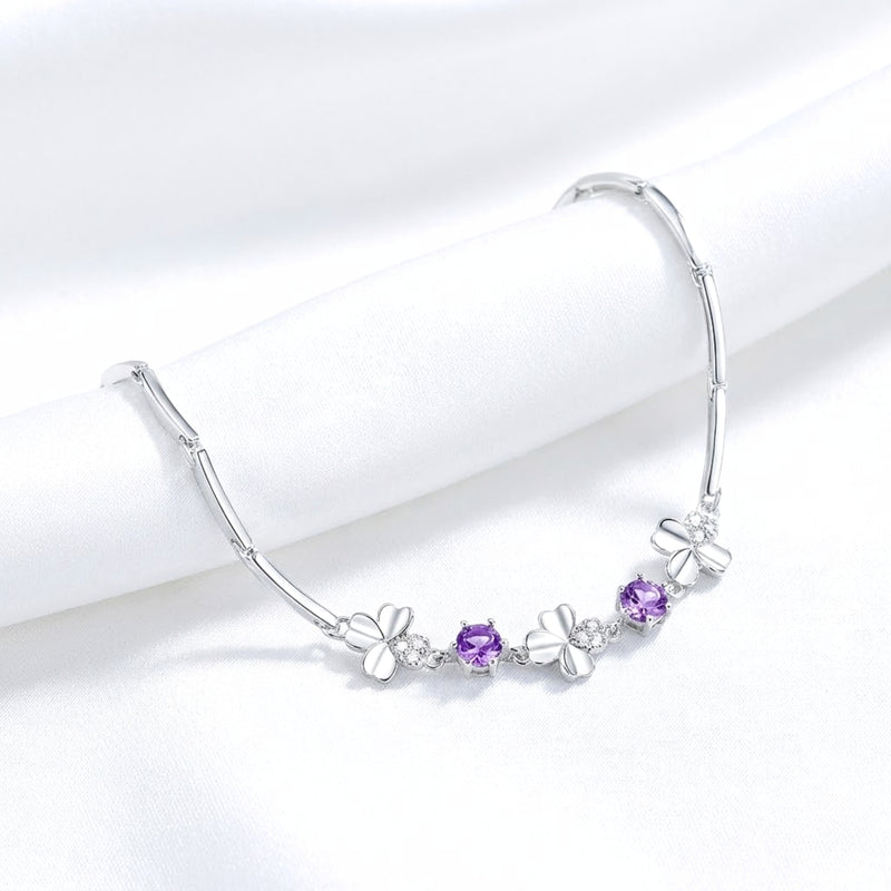 925 sterling silver clover bracelet with round purple simulated amethyst stones draped on white fabric.