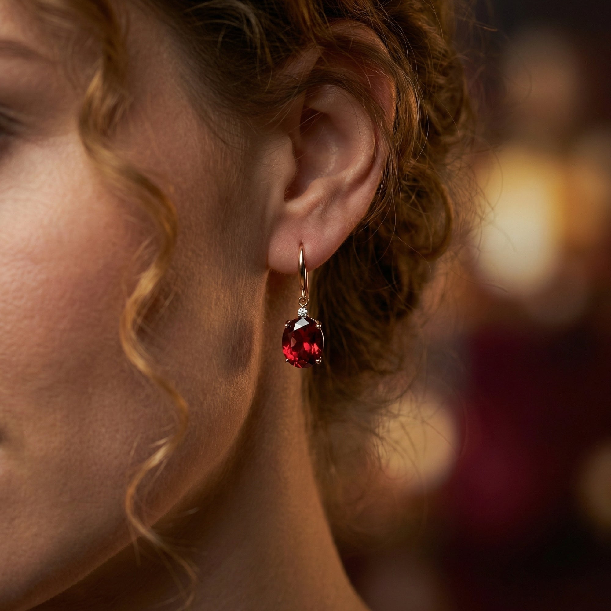 Side profile of a model wearing an 18K rose gold drop earring with an oval cut natural red garnet.