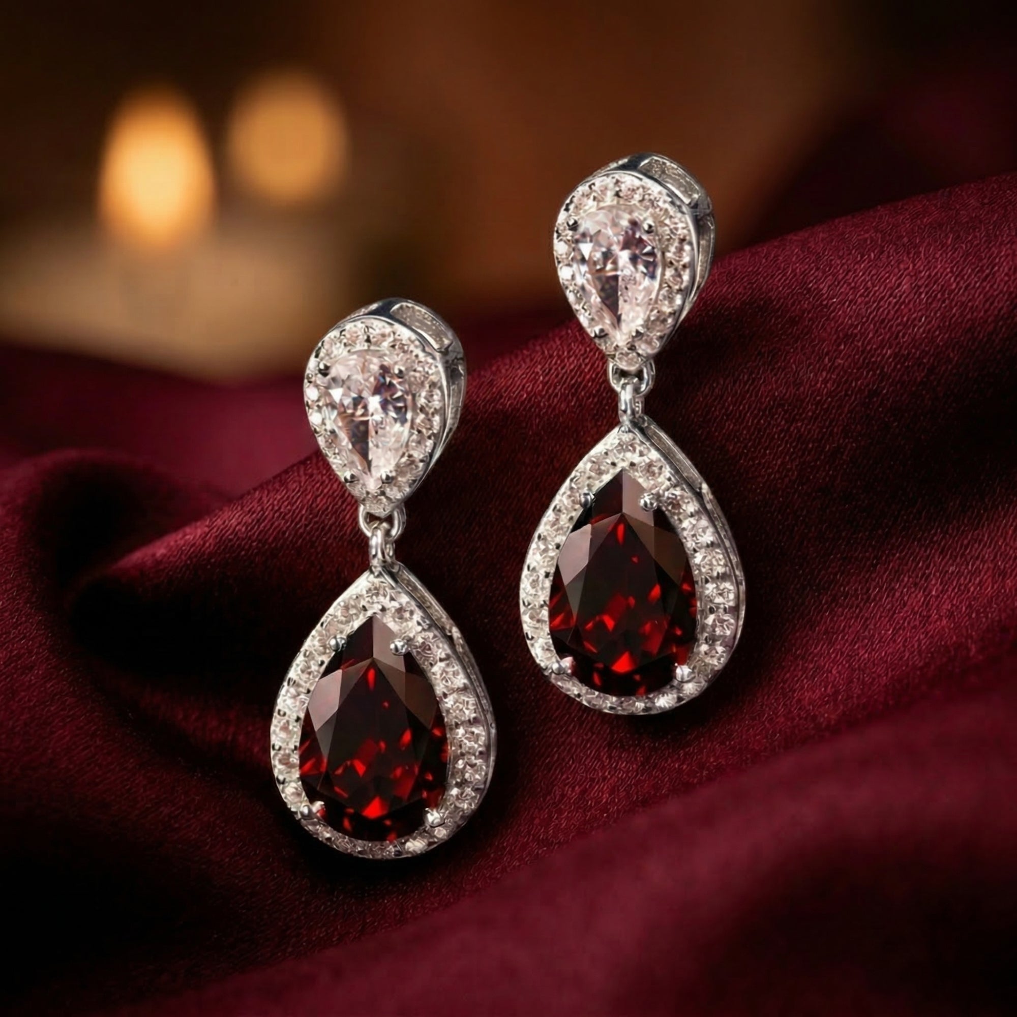 Close-up of Rosaria drop earrings showing the faceted pear red garnet and white metal halo.