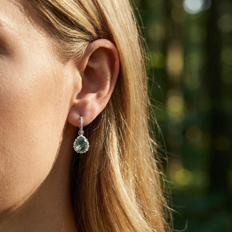 Model wearing a teardrop moss agate halo earring in sterling silver, shown in a natural outdoor setting.