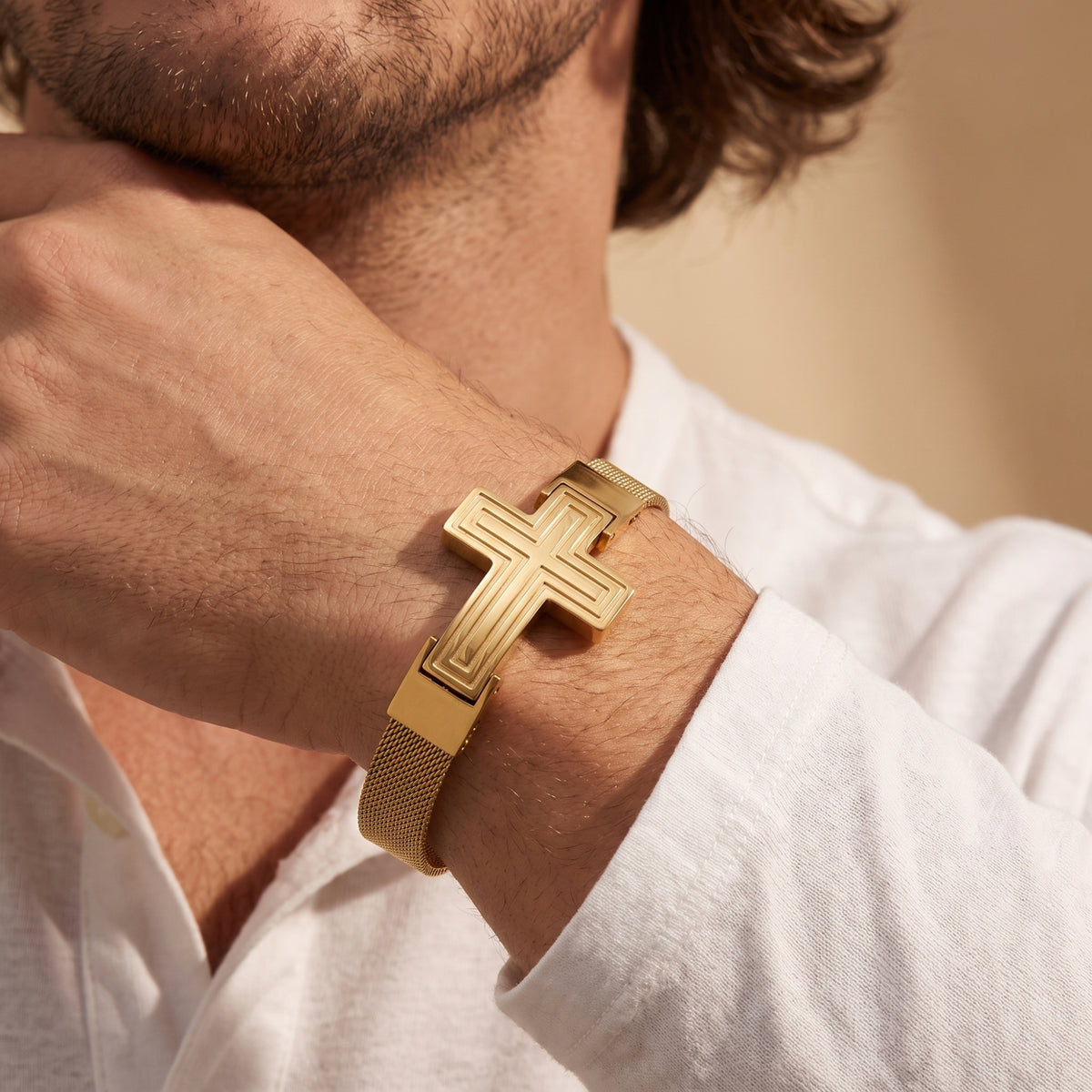 Gold-tone cross mesh bracelet worn on a man's wrist with a white collared shirt.