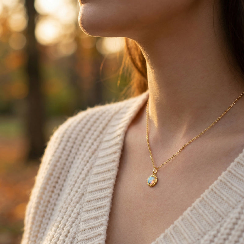 Side profile of a woman wearing the gold-tone round natural opal necklace in a lifestyle setting.